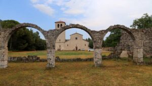 Facciata della basilica dell'Abbazia di San Vincenzo al Volturno vista attraverso gli archi medievali